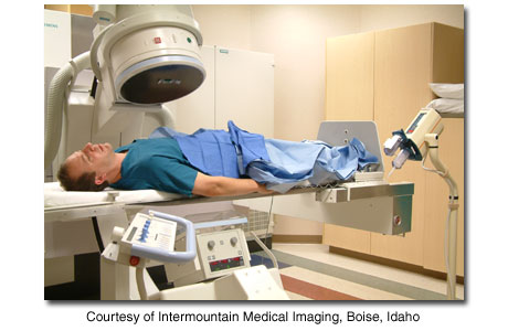 Person lying under X-ray machine in cath lab